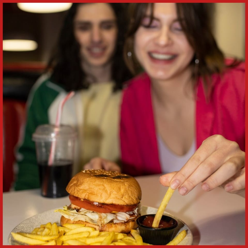 Two smiling people enjoying a Burger Shack burger, fries, and a drink.